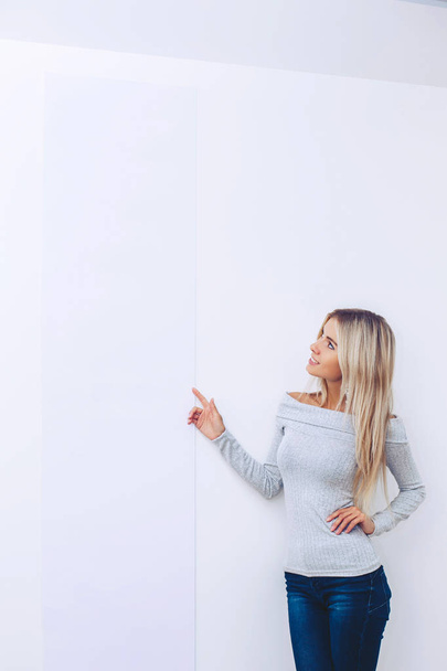 A girl in a sweater and jeans on a white background points a finger - Photo, image