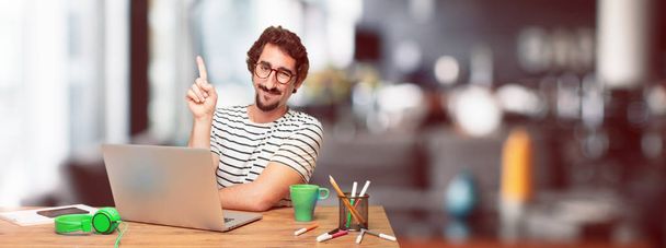 young bearded graphic designer with a laptop smiling and looking satisfied and happy, counting number with one finger. - Foto, Bild