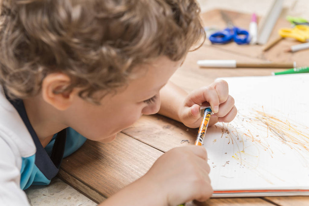 Концепция возвращения в школу. Ребенок точит карандаш на деревянных досках
. - Фото, изображение