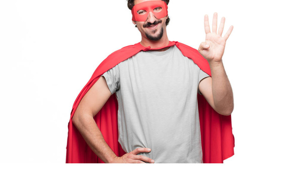Young bearded super hero smiling and looking satisfied and happy, counting number four with fingers. - Photo, Image