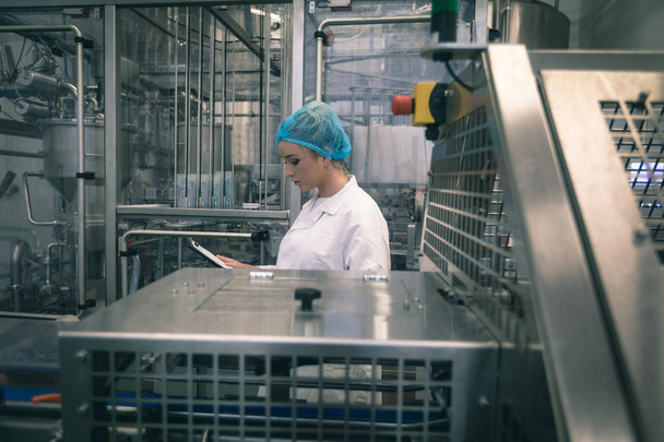 Vrouwelijke werknemer controle machine in de fabriek - Foto, afbeelding