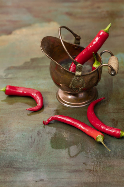 Hot peppers, fresh in a bronze pot, on the wooden background  - Foto, Imagem