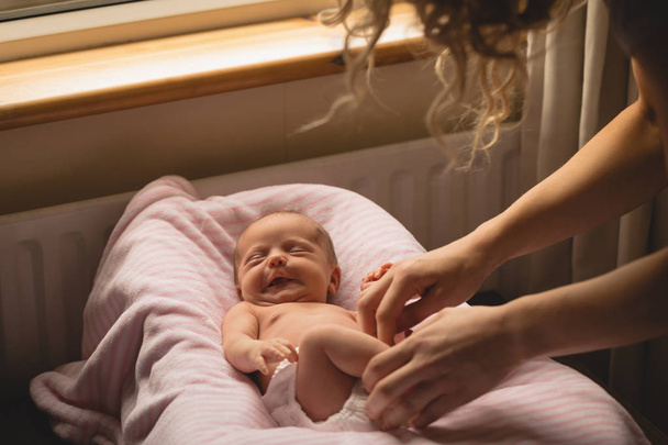 Мать одевает новорожденную девочку в постель
. - Фото, изображение
