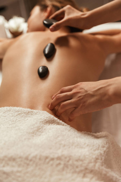 Вид зверху на жінку, що має масаж гарячим каменем у спа-центрі
 - Фото, зображення