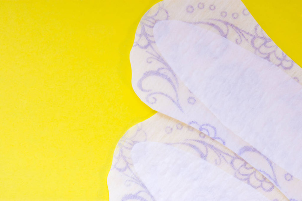 Twee dagelijkse vrouwelijke pads of maandverband (handdoek) zijn op gele achtergrond van de uniforme weergave van bovenaf met duidelijke gebied van halve foto of labels of koppen. Vrouwelijke hygiënische producten voor de gezondheid van de vulvovaginale - Foto, afbeelding