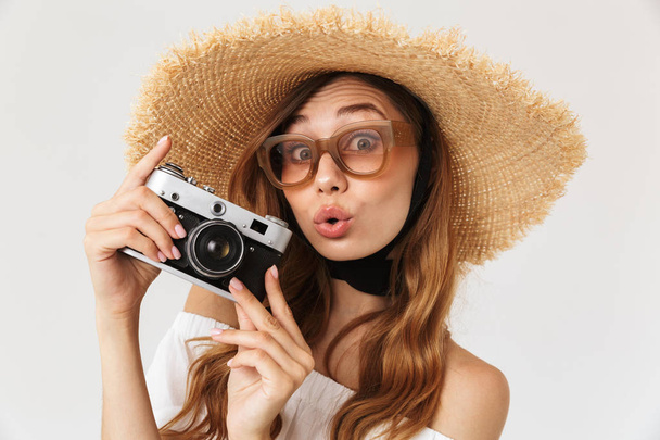 Image of hipster young woman 20s wearing straw hat and sunglasses holding retro camera isolated over white background - Foto, Imagen