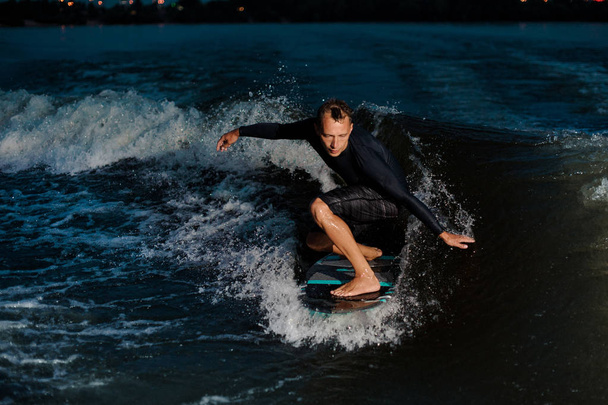 青い川の反対のウェイク ボード上でジャンプ黒水着でアクティブな wakesurfer - 写真・画像