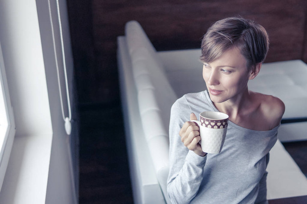 Donna che beve caffè mattutino in una stanza luminosa, immagine vintage tonica
 - Foto, immagini