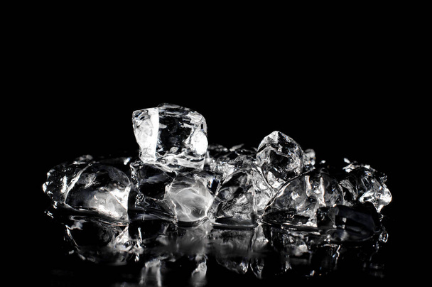 Fresh ice cubes arranged in pile and slowly melting on the dark background of studio - 写真・画像