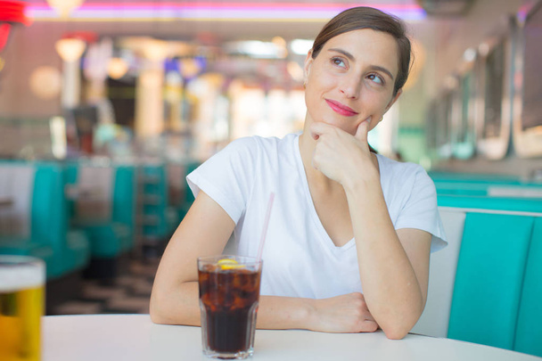 young pretty woman happy and satisfied drinking a cola in an american dinner restaurant - Foto, imagen