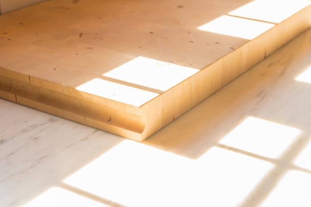 Uma placa de corte de cozinha de madeira em um balcão de cozinha, com uma janela de luz solar brilhando sobre ele
. - Foto, Imagem