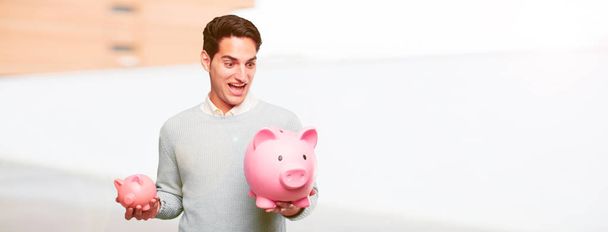 young handsome tanned man with a piggy banks - 写真・画像