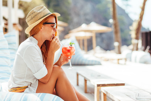Young woman drinking cocktail in a beach bar - Photo, Image