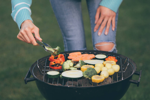 Jeune femme cuisine des légumes pour le barbecue végétarien dîner en plein air, concept de mode de vie végétalien et païen
. - Photo, image