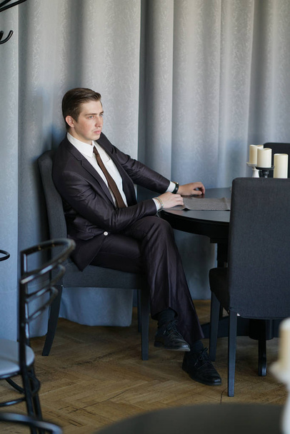 Egy fiatal üzletember jött ebédelni egy kávézóban, ő ül egy asztalnál, és várja, hogy valaki - Fotó, kép
