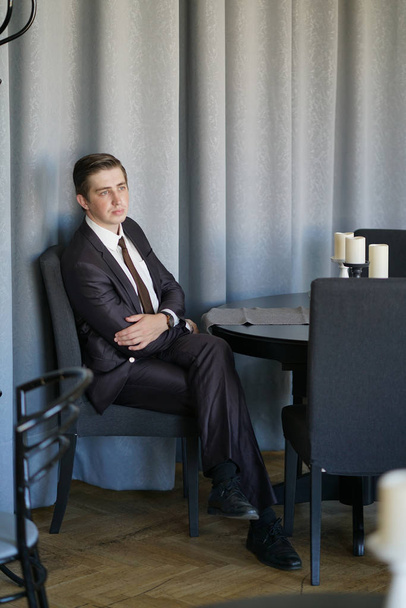 Un giovane uomo d'affari è venuto a pranzo in un caffè, si siede a un tavolo e aspetta qualcuno.
 - Foto, immagini