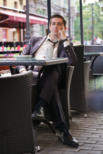 Egy fiatal üzletember jött ebédelni egy kávézóban, ő ül egy asztalnál, és várja, hogy valaki - Fotó, kép