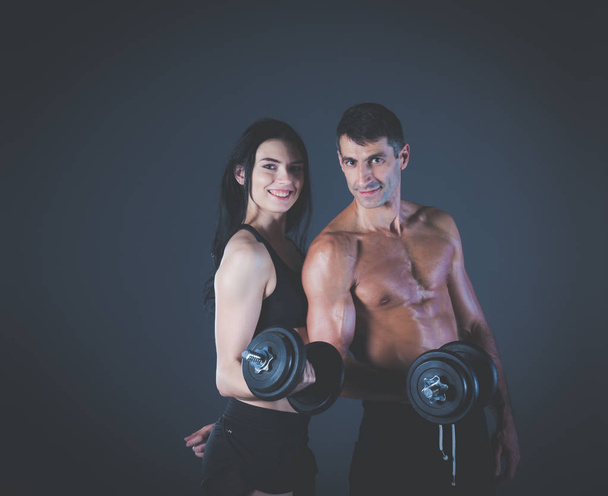 Athletic man and woman with dumb-bells. Personal fitness instructor. Personal training. Weight training. Workout. - Photo, Image