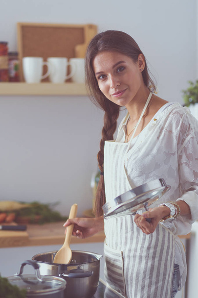 Mutfakta ahşap kaşıkla yemek pişiren kadın. Aşçı kadın. - Fotoğraf, Görsel