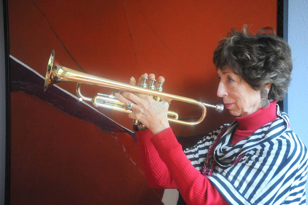 Női senior jazz trombita játékos fúj ő kürt beltéri. - Fotó, kép