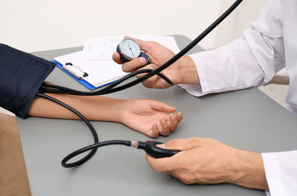 Medico che controlla la pressione sanguigna del paziente al tavolo in ufficio, primo piano
 - Foto, immagini