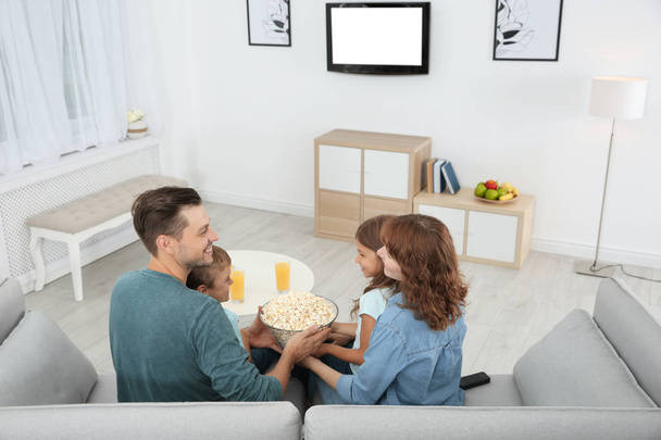 Family watching TV with popcorn in room - Valokuva, kuva