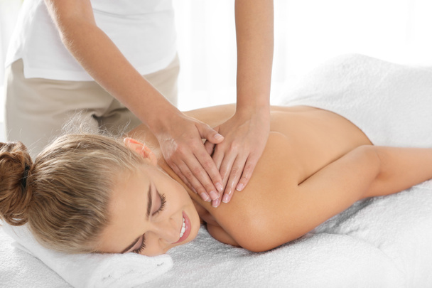 Relaxed woman receiving shoulders massage in wellness center - Foto, Imagen