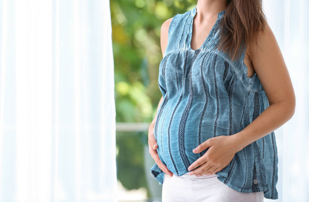 Kobieta w ciąży, stojący w pobliżu okna w domu, zbliżenie - Zdjęcie, obraz