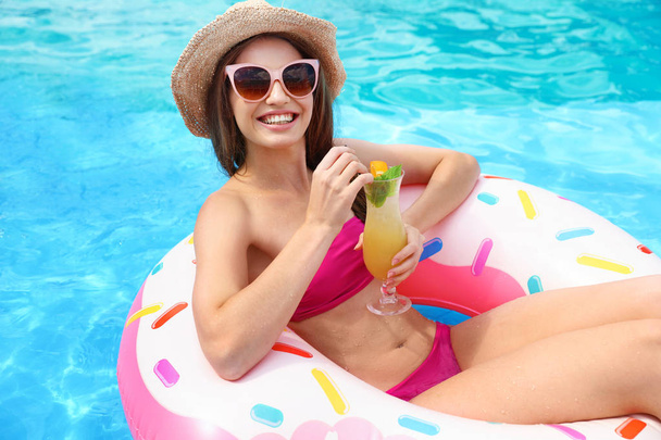 Молода жінка з коктейлем в басейні в сонячний день
 - Фото, зображення