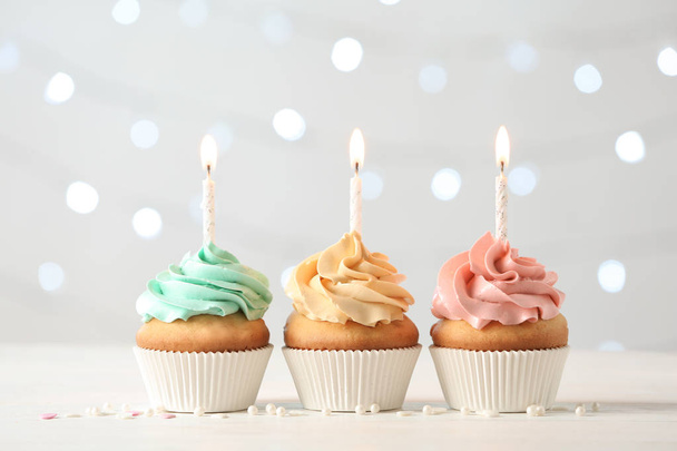 Deliciosos cupcakes de cumpleaños con velas encendidas sobre un fondo de luces borrosas
 - Foto, imagen