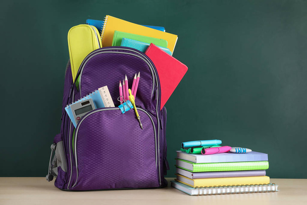Color backpack and stationery on table near chalkboard with space for text. Ready for school - Fotoğraf, Görsel