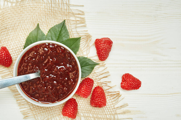 Raspberries jam with fresh red ripe on wooden background with napkin. Top view. - Foto, Bild