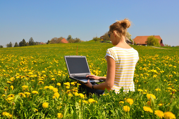 Fille avec un ordinateur portable sur la prairie de printemps
 - Photo, image