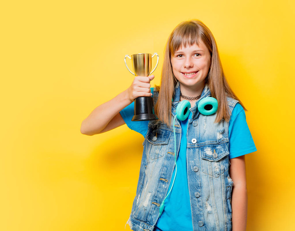 улыбающаяся девочка-подросток с золотой чашкой
 - Фото, изображение