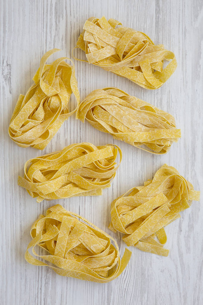 Uncooked pasta pappardelle on a white wooden table, top view. Overhead, flat lay.  - Photo, Image