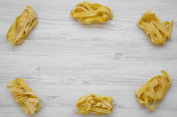 Frame of raw pasta pappardelle. White wooden background. Space for text. - Photo, Image