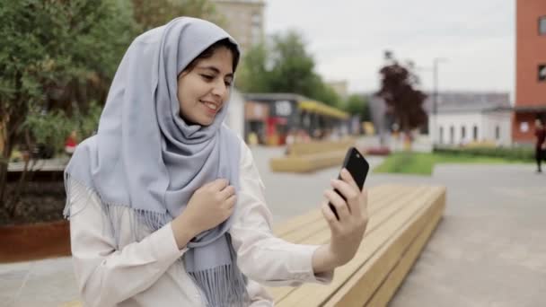 Young woman in hijab making a selfie in a summer street - Felvétel, videó