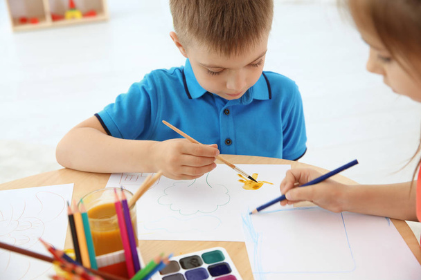 Cute little children painting at table in playing room - Foto, Imagen