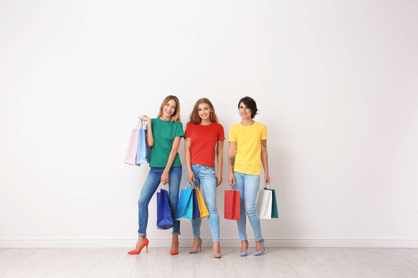 Group of young women with shopping bags near light wall - Fotografie, Obrázek