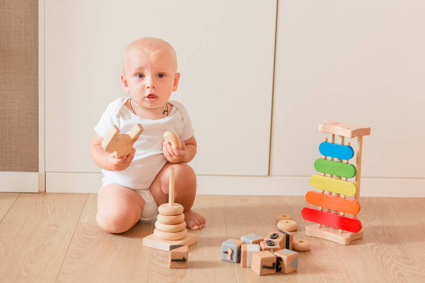 Cute little baby boy playing with stacking rings in the room - Φωτογραφία, εικόνα