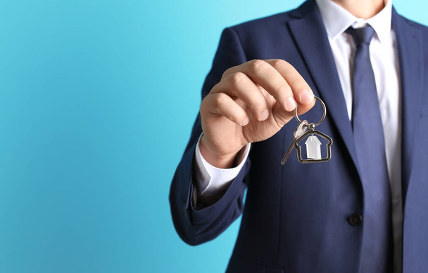 Real estate agent holding key on color background, closeup - Photo, Image