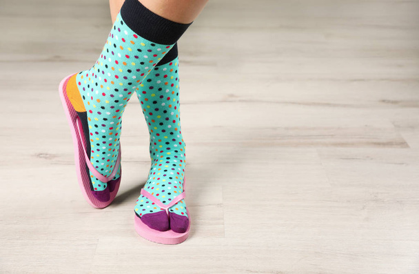 Woman wearing bright socks with flip-flops standing on floor. Space for design - Foto, Imagem