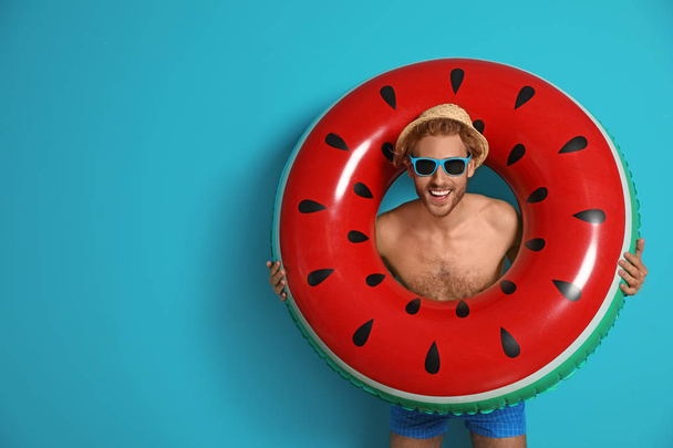 Happy young man with inflatable ring on color background - Фото, изображение