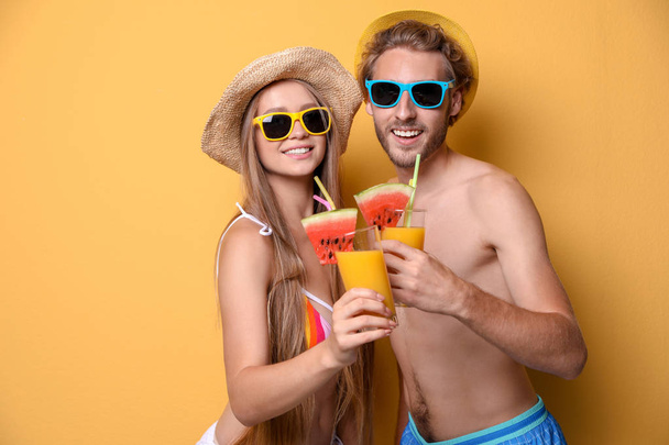 Young couple in beachwear with cocktails on color background - Фото, изображение