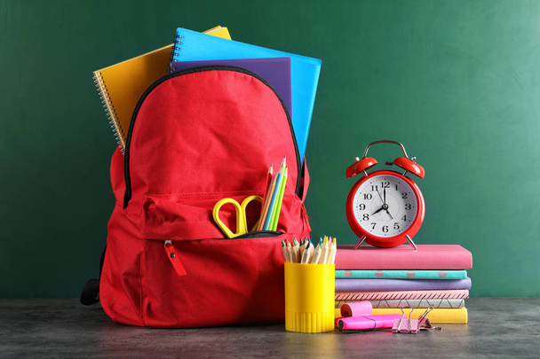 Рюкзак со школьными принадлежностями на столе против доски
 - Фото, изображение