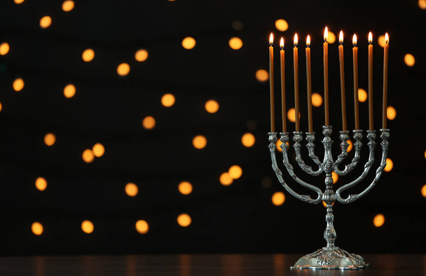 Hanukkah menorah with candles on table against blurred lights - Fotoğraf, Görsel
