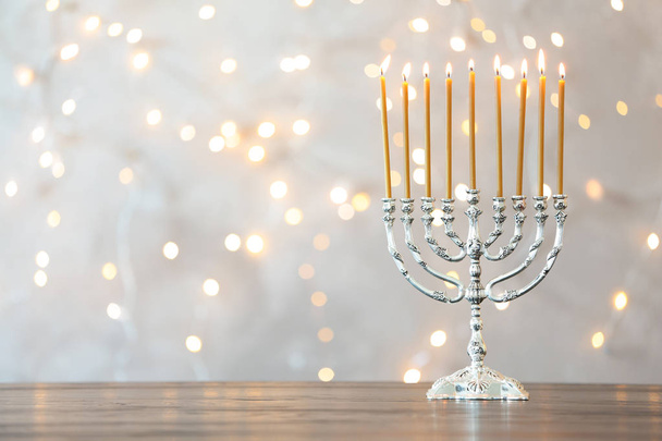 Hanukkah menorah with candles on table against blurred lights - Foto, imagen