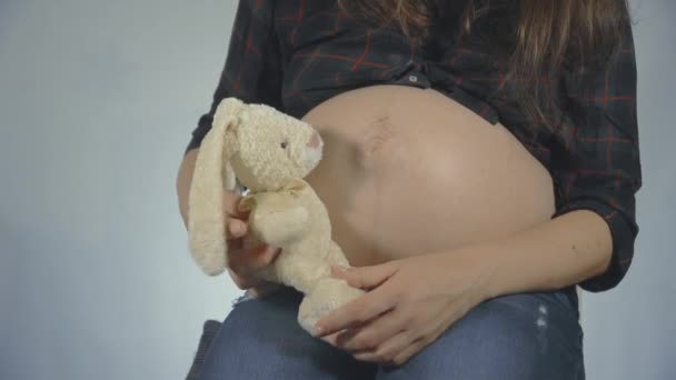 Terhes nő játszik egy nyuszi plüss játék pózol - Felvétel, videó