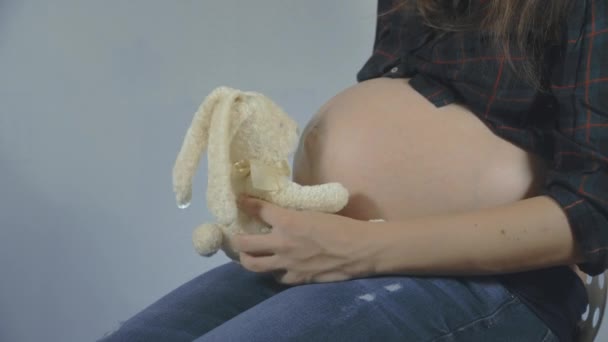 Kobieta w ciąży, grając z bunny pluszowe zabawki stwarzające - Materiał filmowy, wideo