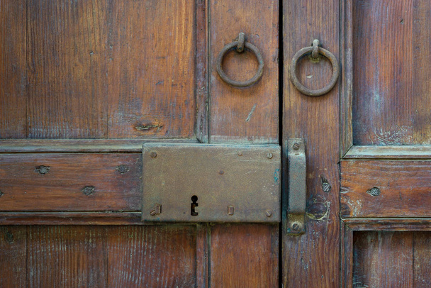 Primer plano de un pestillo envejecido de madera y dos golpeadores de puerta de anillo oxidado sobre una puerta de madera ornamentada, El Cairo, Egipto
 - Foto, Imagen
